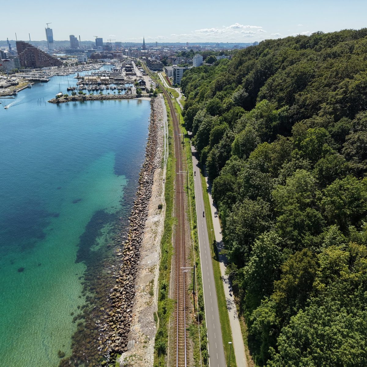 Aerial view along the Aarhus coastline looking back toward the harbour and city skyline