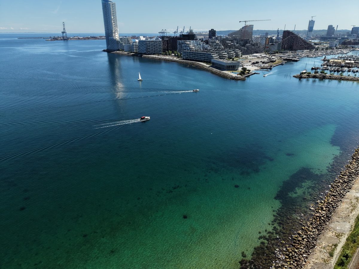 Aerial view of the Aarhus Ø waterfront and marina, with the wave-shaped tower and moored boats